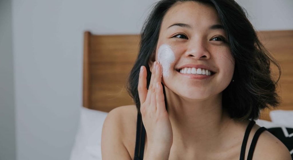 Girl smiling while applying cream
